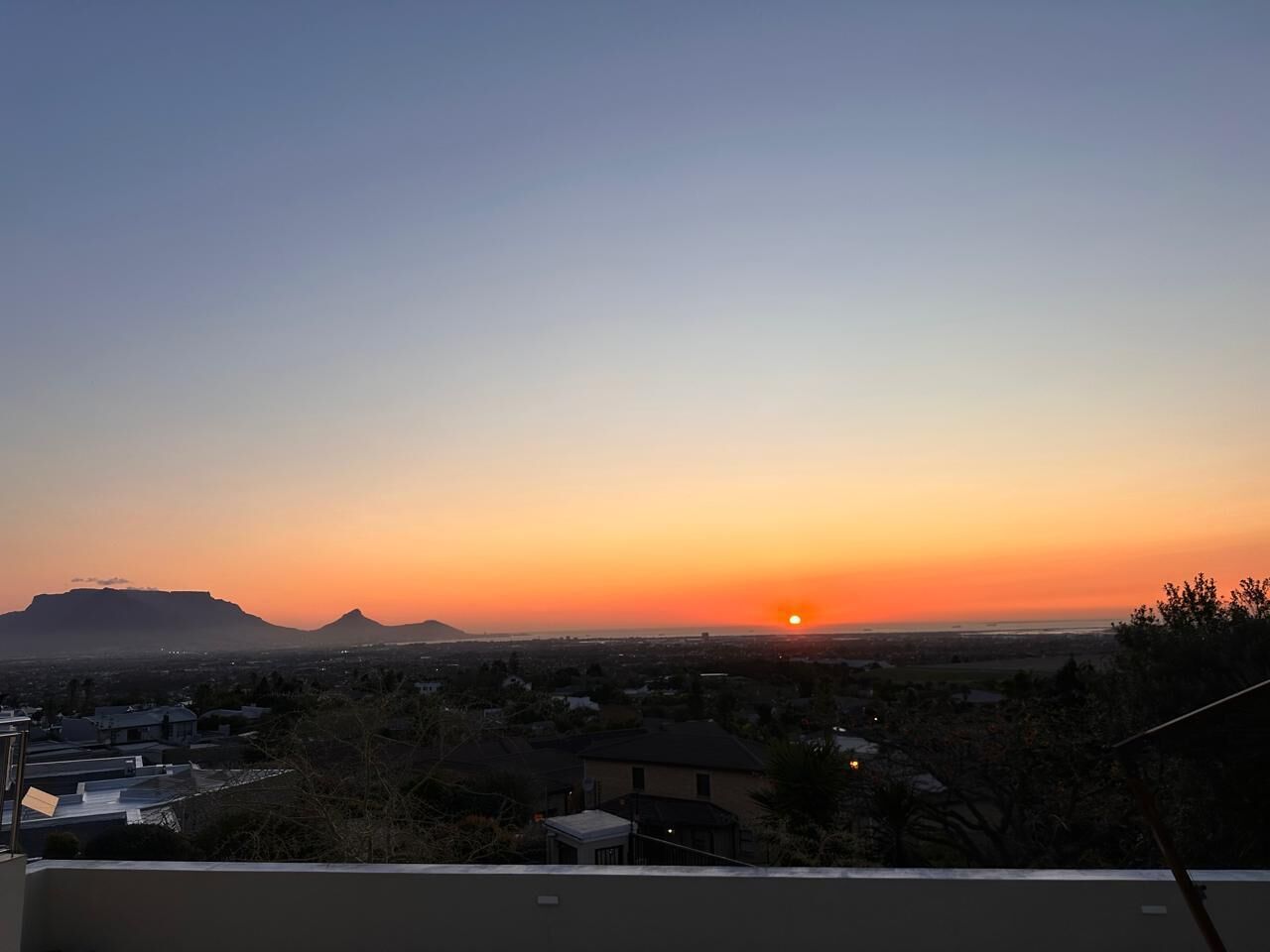 Un atardecer sobre un paisaje urbano con edificios y montañas al fondo.