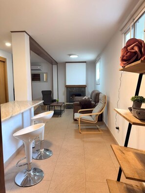 Ein modernes Wohnzimmer mit Kamin, einer Couch und einer Essecke mit Barhocker.