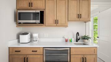 A kitchen with wooden cabinets, a microwave, a toaster, a dishwasher, a sink, and a window with a view.
