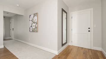 Un couloir avec une porte blanche, un miroir et un tableau accroché au mur.