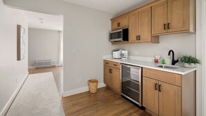 Una cocina moderna con armarios de madera, microondas, lavavajillas y un lavaplatos.