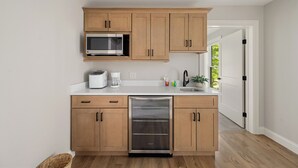 Una cocina moderna con armarios de madera, microondas integrado, lavavajillas y cafetera.