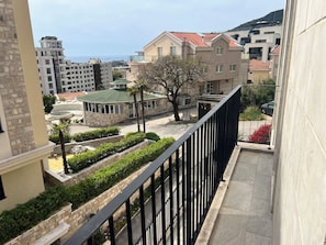 A residential area with a building featuring a green roof, a stone facade, and a balcony with a metal railing.