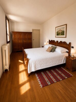 Una camera da letto con un letto in legno, un termosifone, un armadio e un quadro appeso al muro.