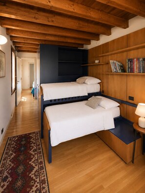 A room with a bunk bed, a bedside table with a lamp, a bookshelf, and a patterned rug. - Historic Palazzo with Pool & Castle View (Sanguinetto)