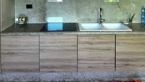 A modern kitchen with wooden cabinets, a granite countertop, and a stainless steel sink. - Historic Palazzo with Pool & Castle View (Sanguinetto)