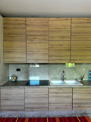Una cucina moderna con mobili in legno, un piano di lavoro in granito e un lavello in acciaio inossidabile.
