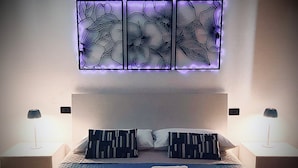 Een slaapkamer met een bed, twee nachtkastjes, een wandlamp en een decoratief paneel boven het bed.