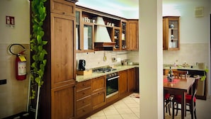 Een keuken met houten kastjes, een fornuis en een eethoek met stoelen.