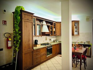 Una cucina con mobili in legno, un fornello e una zona pranzo con sedie.