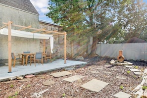 A patio with a wooden pergola, outdoor seating, and a fire pit area.