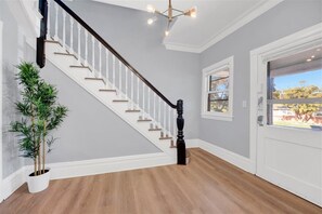 A staircase with white balusters and a dark balustrade, a potted plant, and a door with a window.