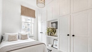 Une chambre à coucher avec un lit, une fenêtre donnant sur un beau paysage, des murs blancs et une porte.