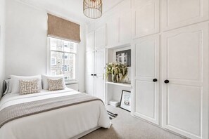 Ein Schlafzimmer mit Bett, Fenster mit Blick, weißen Wänden und einer Tür.