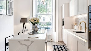 Une cuisine moderne dotée d’un îlot en marbre, d’une fenêtre offrant une vue agréable et de meubles blancs.