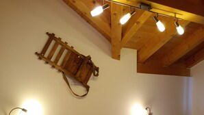 Une chambre à coucher avec un lit en bois, deux tables de chevet, une commode, une décoration murale faite de lattes de bois et deux lampes fixées au mur.