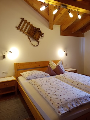 Ein Schlafzimmer mit einem hölzernen Bett, zwei Nachttischen, einer Wanddekoration aus Holzleisten und zwei Wandlampen.