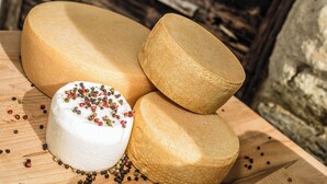 Une surface en bois sur laquelle se trouvent une grande portion de fromage blanc et trois autres portions de fromage.