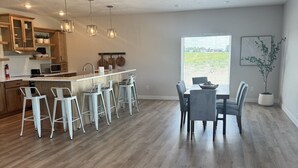 A spacious kitchen with a central island, bar stools, and a dining area with a table and chairs.