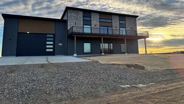 A modern two-story house with a garage, a balcony, and a driveway leading to the entrance.