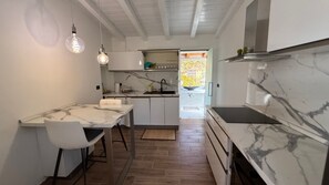 Eine moderne Küche mit Marmorarbeitsplatten, einem Essbereich mit weißem Tisch und Stühlen sowie Pendelleuchten.