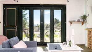 A living room with a sofa, a coffee table, and a sliding glass door leading to an outdoor patio. - Studio Aspilon Pool and Mountain Views Near Drama (Drama)