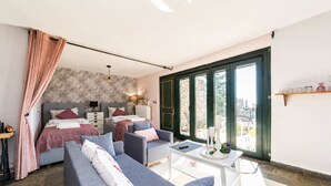 A modern bedroom with a bed, two armchairs, a sofa, a bedside table, and a large window. - Studio Aspilon Pool and Mountain Views Near Drama (Drama)