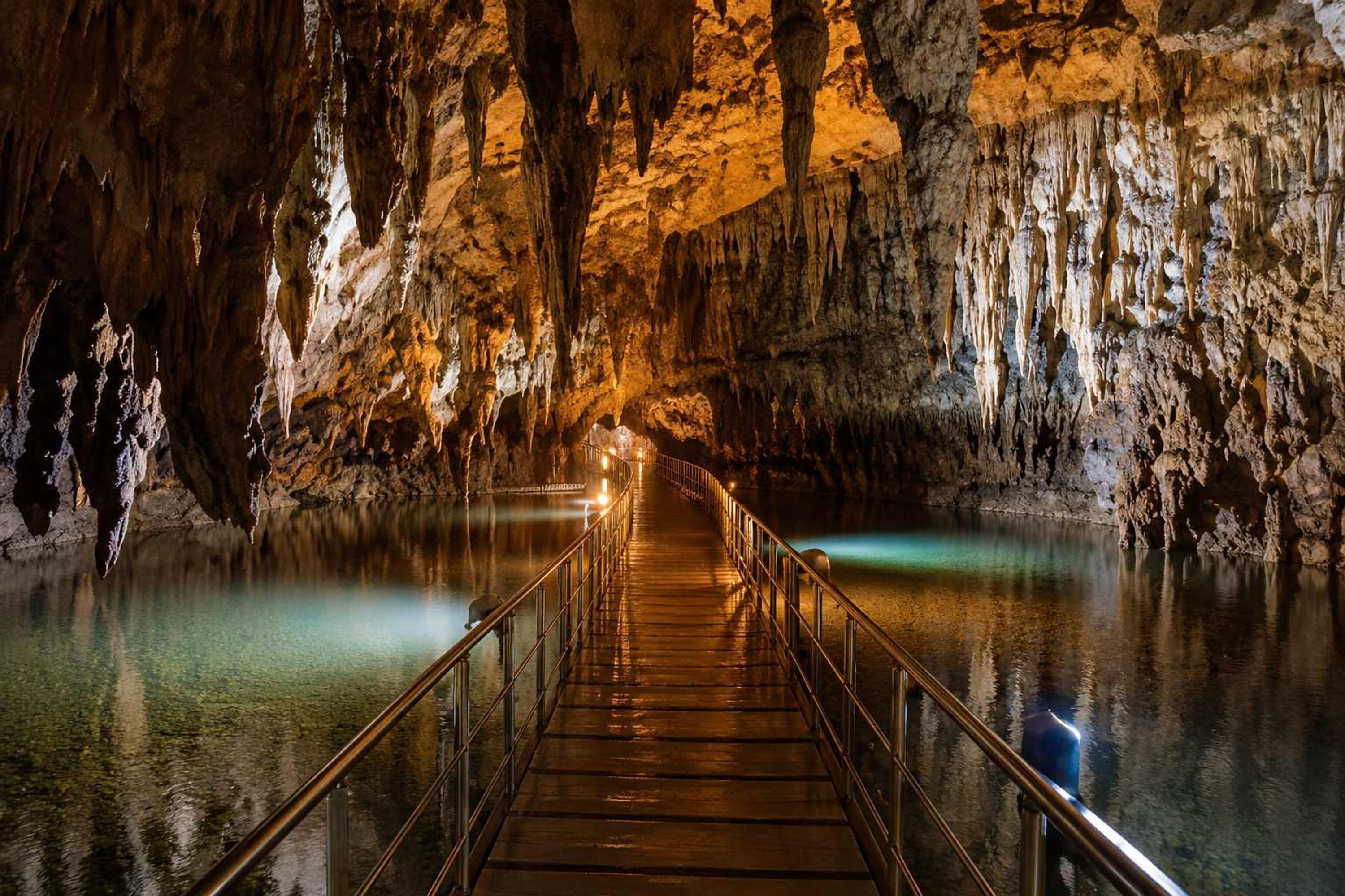 A cave with a wooden walkway and metal railings.