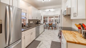Una cocina moderna con electrodomésticos de acero inoxidable, armarios blancos, encimera de madera y una zona de comedor con mesa y sillas.