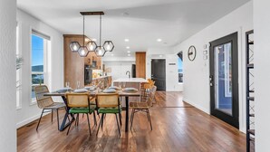 A modern kitchen with wooden cabinets, a dining area with wicker chairs, and a large window. - Reno Retreat - 3BR Oasis w Swim Spa Hot Tub (Reno)