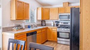 Una cocina con armarios de madera, lavavajillas, estufa y microondas.