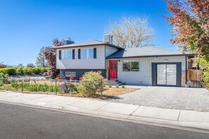 A two-story house with a red door, a garage, and a landscaped front yard. - Spacious Pet-friendly Retreat 4BR Grill 5 Beds (Reno)
