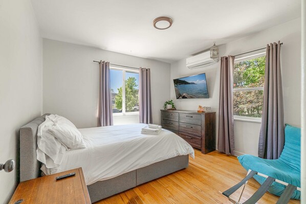 A bedroom with a bed, dresser, chair, and a window with curtains. - Midtown Sanctuary w Pac-man (Reno)