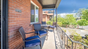 A brick building with a balcony, outdoor seating with chairs and tables, and a view of trees and buildings in the background. - Midtown Sanctuary w Pac-man (Reno)