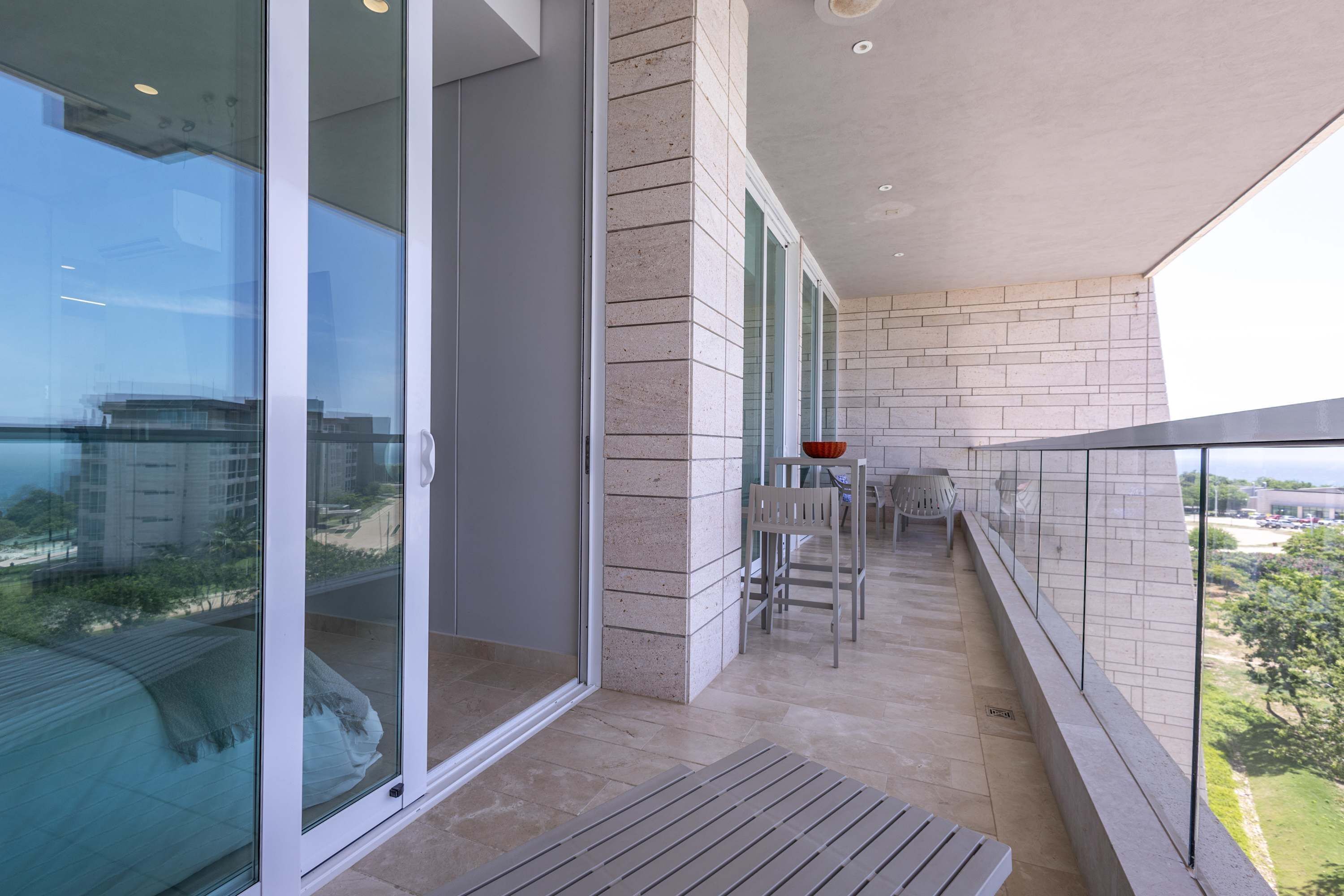 A balcony with a view of the city, a table with chairs, and a bench.