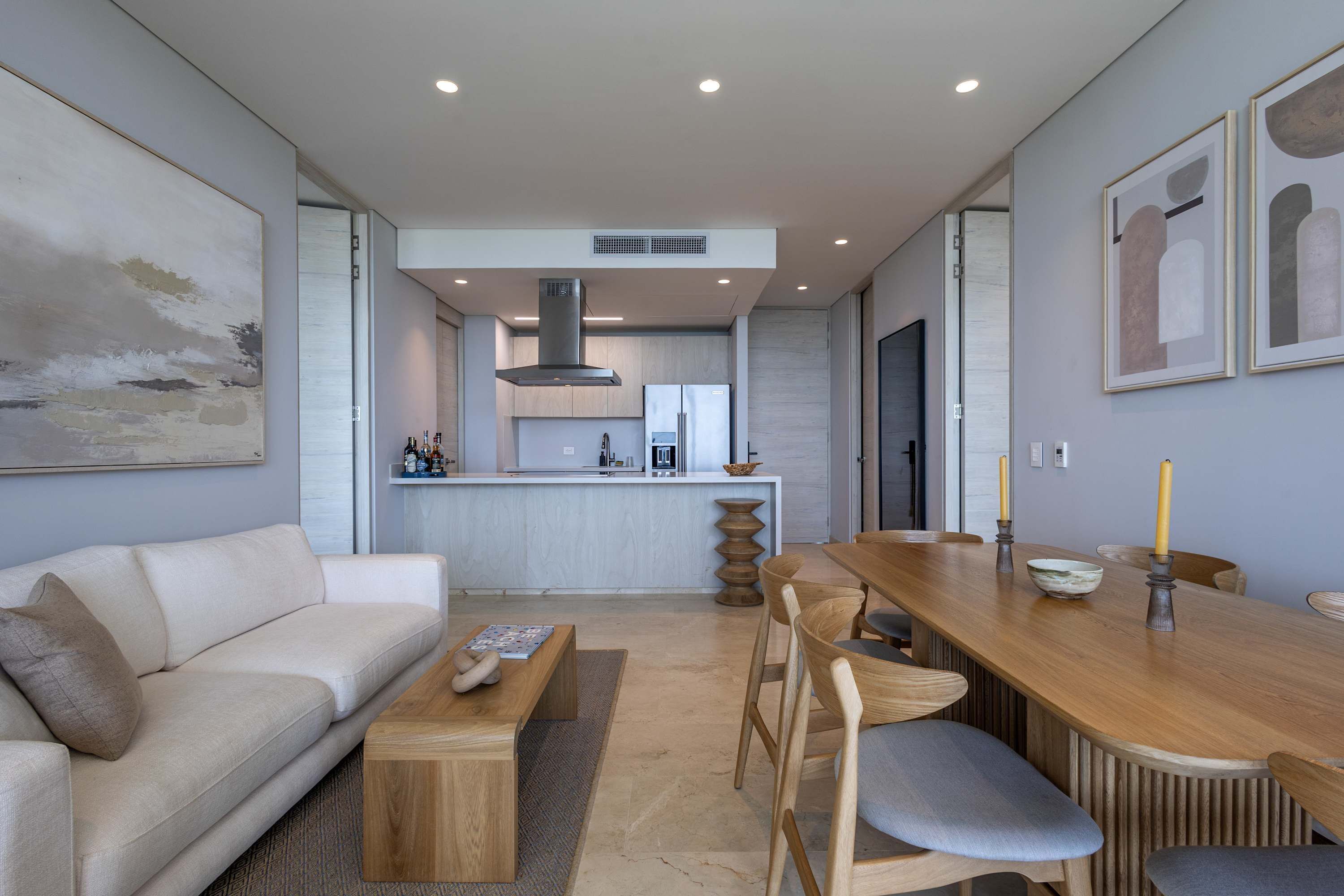 Un salon moderne avec un canapé, une table basse, une table à manger avec des chaises, et une cuisine en arrière-plan.