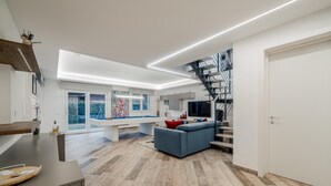 A modern living room with a pool table, a blue sofa, and a staircase leading to an upper level. - Villa Padana (Piumazzo)