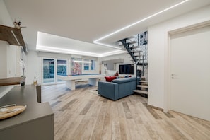 A modern living room with a pool table, a blue sofa, and a staircase leading to an upper level. - Villa Padana (Piumazzo)