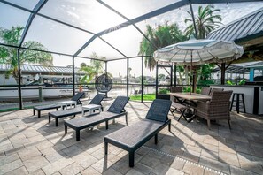 Eine Terrasse im Freien mit Lounge-Möbeln, einem Esstisch und Sonnenschirmen.