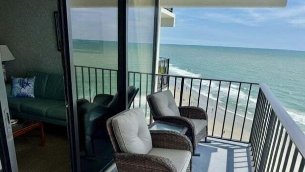 Ein Balkon mit Korbstühlen, einer Couch und Blick aufs Meer.