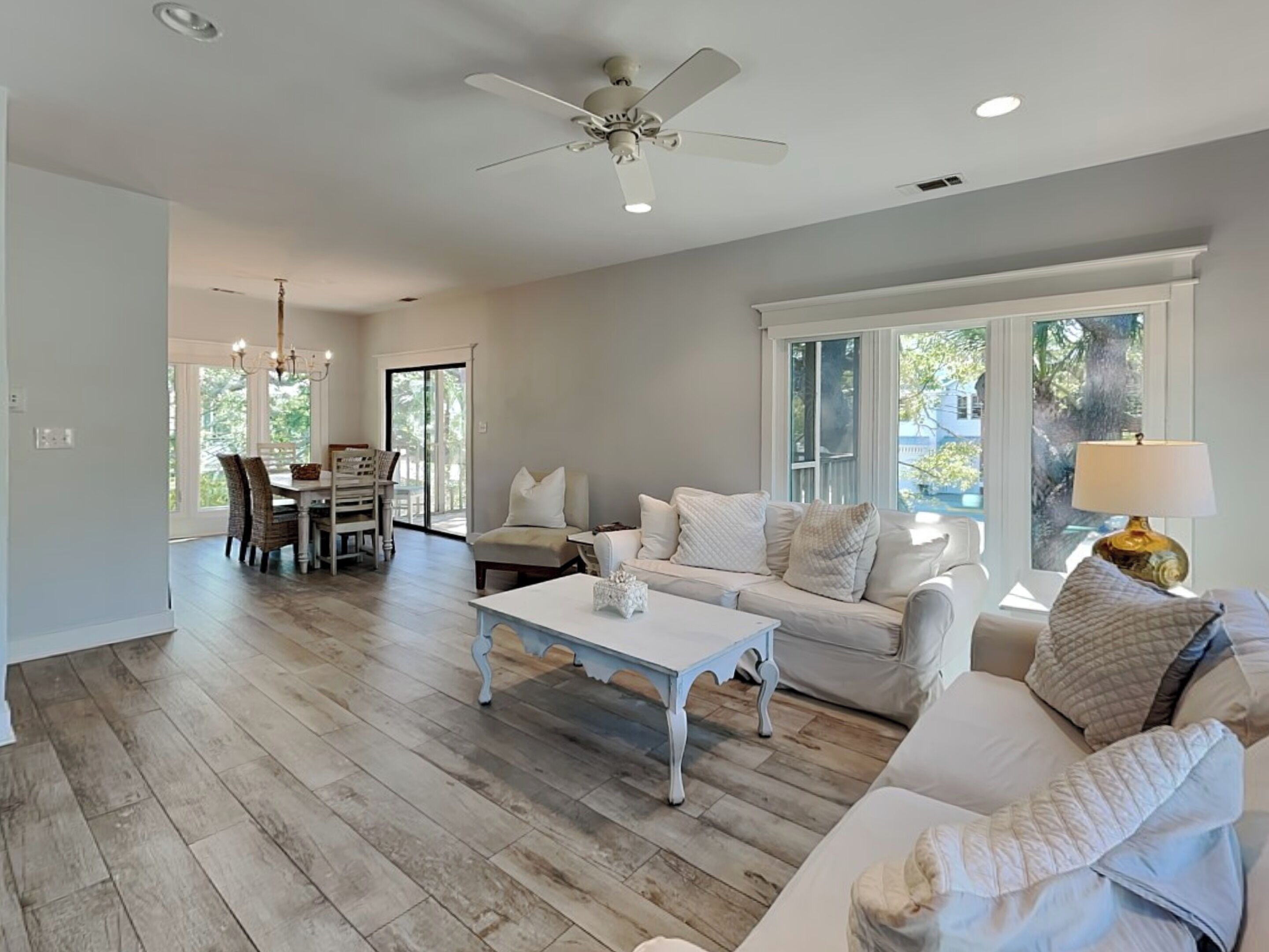 A spacious living room with a white sofa, a coffee table, and a dining area with chairs and a table.