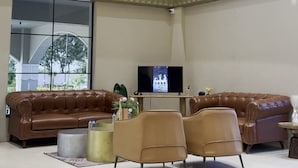 Amplia sala de estar con un ventanal grande, televisor de pantalla plana, sofás de cuero y un diseño moderno de techo.