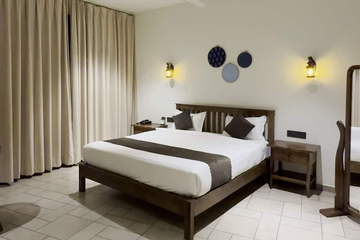 Habitación de hotel moderna con una cama grande, un ventilador de techo y lámparas fijadas a la pared.
