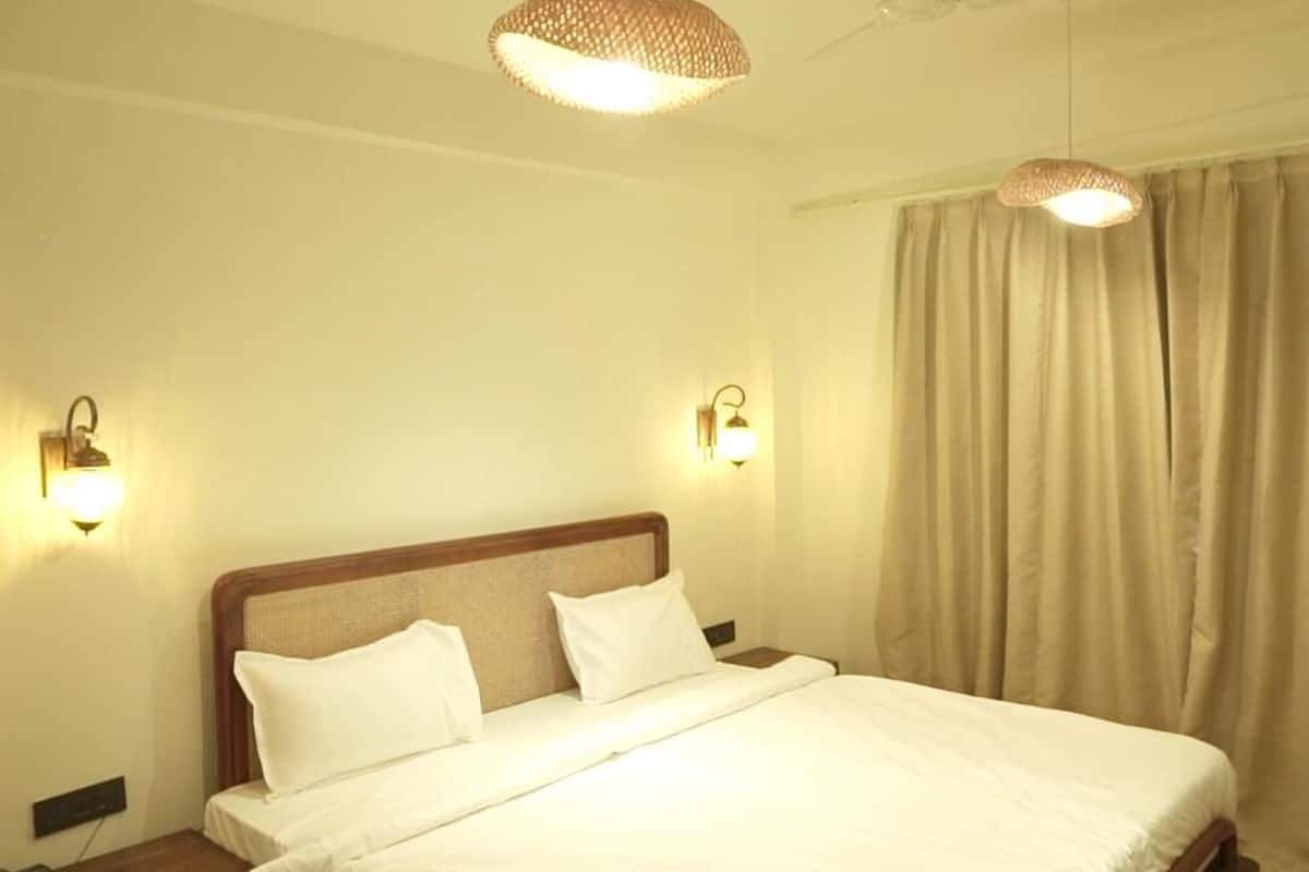 Habitación de hotel con una cama grande, dos lámparas de pared, un ventilador de techo y una mesita de noche con un teléfono.