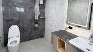 Ein modernes Badezimmer mit Toilette, Dusche, Waschbecken und Spiegel.