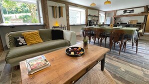 Ein gemütliches Wohnzimmer mit einer Couch, einem Couchtisch mit einer Obstschale und einem Essbereich mit Stühlen und einem Tisch.