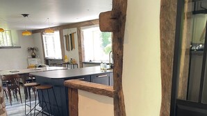 Eine moderne Küche mit einer zentralen Kochinsel, Holzbalken und einer Essecke mit Hockern.
