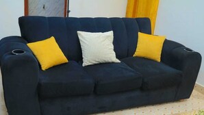 Ein dunkelblaues Sofa mit zwei gelben und einem weißen Kissen.