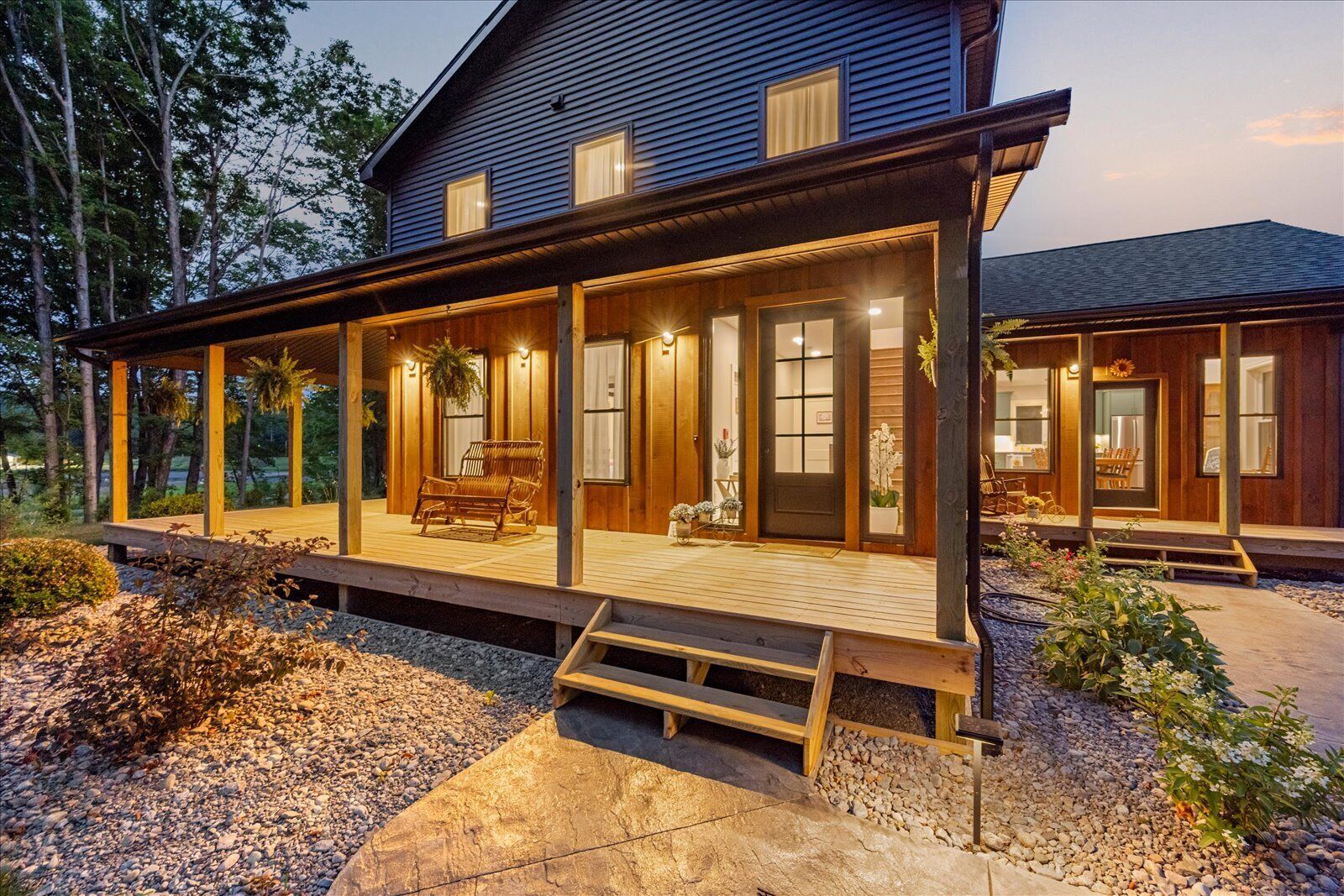A two-story house with a covered porch, a front door, and a small garden area.