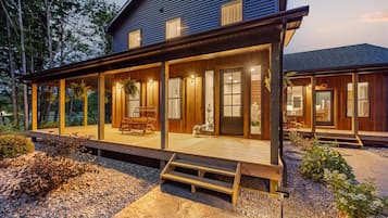 A two-story house with a covered porch, a front door, and a small garden area.